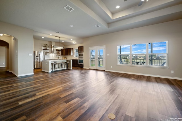 unfurnished living room with ceiling fan, dark hardwood / wood-style flooring, a wealth of natural light, and french doors