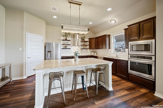 kitchen featuring a kitchen bar, light stone countertops, decorative backsplash, a kitchen island, and stainless steel appliances