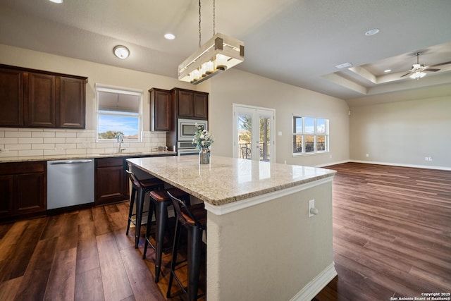 kitchen featuring a kitchen island, decorative light fixtures, stainless steel appliances, a kitchen breakfast bar, and backsplash