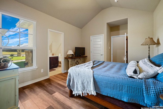 bedroom with hardwood / wood-style flooring, connected bathroom, and lofted ceiling