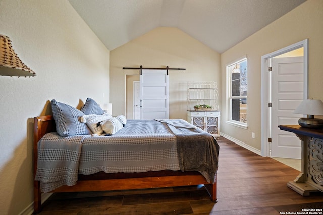 bedroom with dark hardwood / wood-style flooring, a barn door, and vaulted ceiling