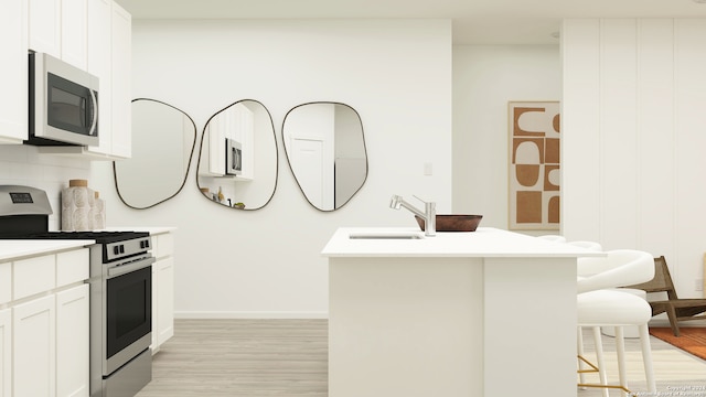 kitchen featuring appliances with stainless steel finishes, white cabinetry, sink, a breakfast bar, and a center island with sink