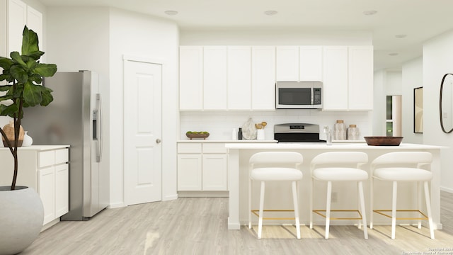 kitchen with backsplash, white cabinets, a kitchen bar, and stainless steel appliances