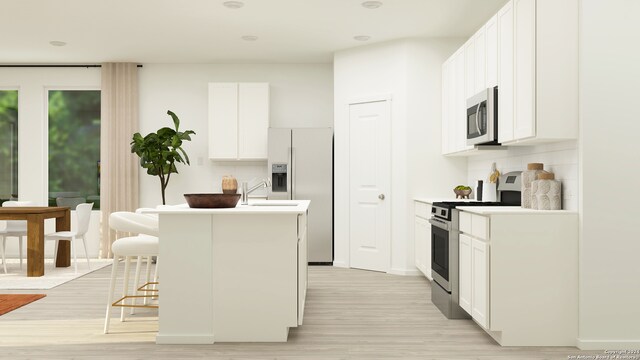 kitchen featuring stainless steel appliances, white cabinetry, a kitchen island with sink, and tasteful backsplash