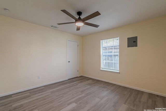 empty room featuring ceiling fan, light hardwood / wood-style flooring, and electric panel