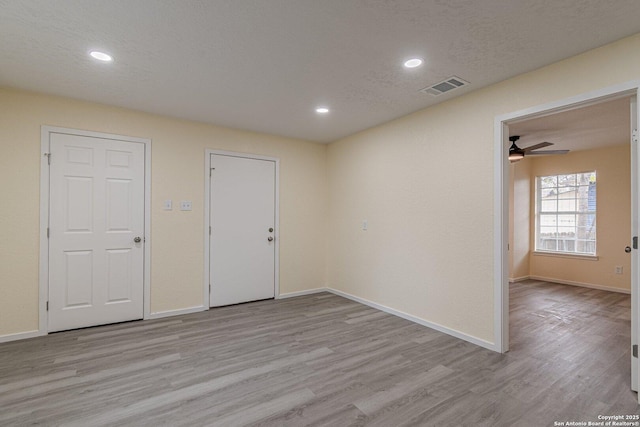 empty room with a textured ceiling and light hardwood / wood-style flooring