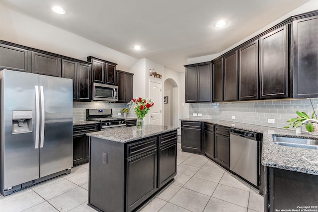 kitchen with dark brown cabinetry, appliances with stainless steel finishes, a center island, sink, and light tile patterned floors