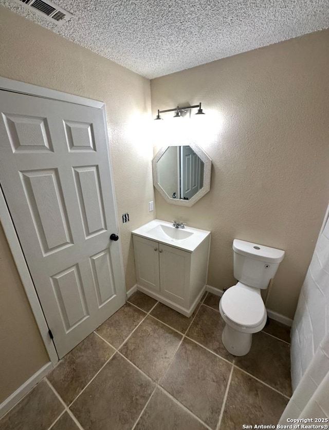 bathroom with vanity, tile patterned flooring, toilet, and a textured ceiling