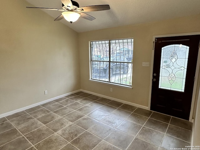 entryway with ceiling fan, dark tile patterned floors, a textured ceiling, and lofted ceiling