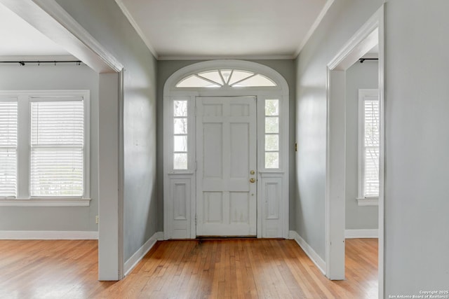 entrance foyer with crown molding, a healthy amount of sunlight, and light hardwood / wood-style flooring