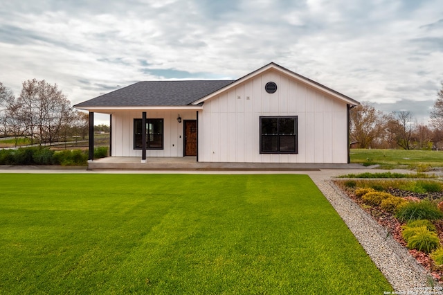 back of property with covered porch and a lawn