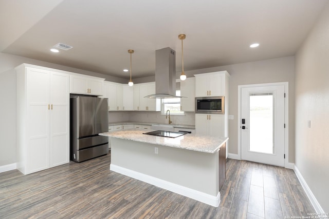 kitchen with pendant lighting, white cabinetry, a kitchen island, island range hood, and stainless steel appliances