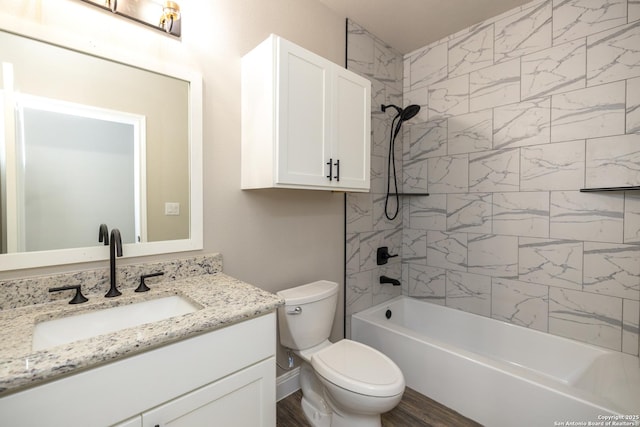 full bathroom featuring wood-type flooring, tiled shower / bath combo, vanity, and toilet