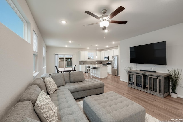 living room with light hardwood / wood-style floors and ceiling fan