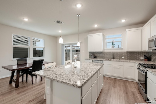 kitchen featuring white cabinets, pendant lighting, appliances with stainless steel finishes, and sink