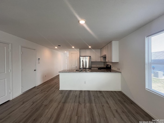 kitchen with kitchen peninsula, dark wood-type flooring, white cabinetry, electric range oven, and stainless steel refrigerator