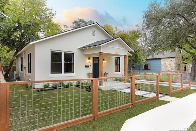 view of front of house with central AC and a yard