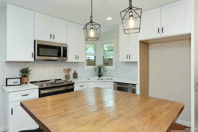 kitchen with pendant lighting, white cabinets, stainless steel appliances, tasteful backsplash, and sink