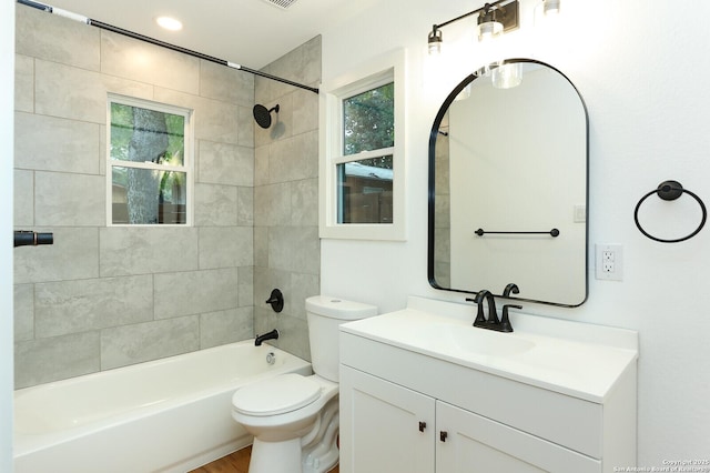 full bathroom featuring tiled shower / bath combo, vanity, and toilet