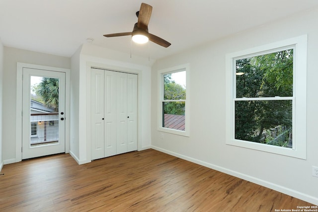 unfurnished bedroom featuring ceiling fan, hardwood / wood-style flooring, and multiple windows