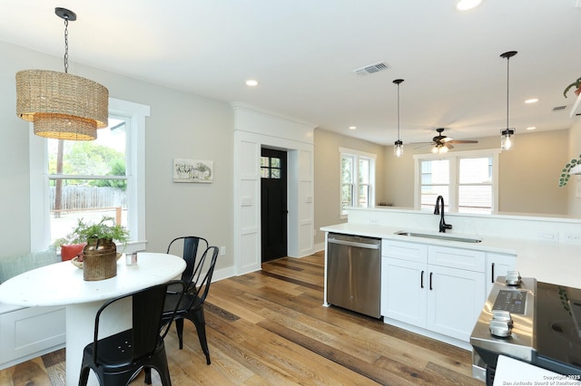 kitchen with sink, white cabinets, light wood-type flooring, decorative light fixtures, and stainless steel appliances