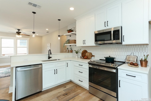 kitchen featuring pendant lighting, white cabinetry, stainless steel appliances, sink, and kitchen peninsula