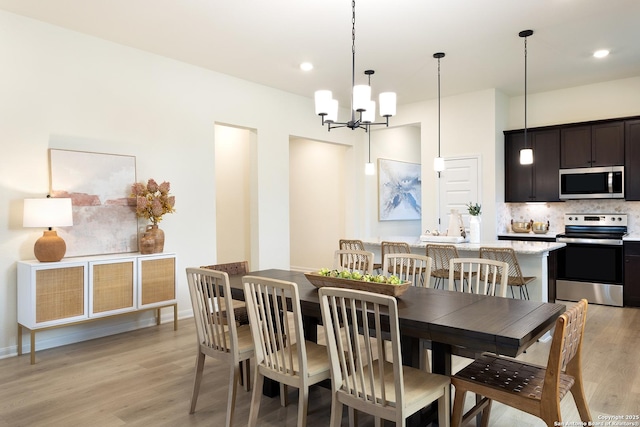 dining area with an inviting chandelier and light hardwood / wood-style flooring