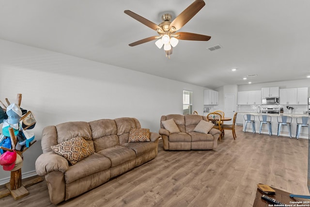 living room with light wood-type flooring and ceiling fan