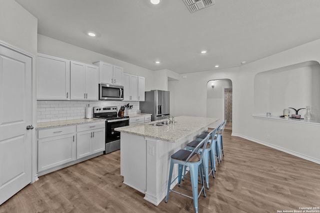 kitchen with sink, white cabinets, a center island with sink, and stainless steel appliances