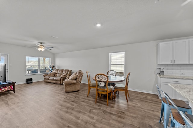 dining area featuring ceiling fan, light hardwood / wood-style floors, vaulted ceiling, and a wealth of natural light