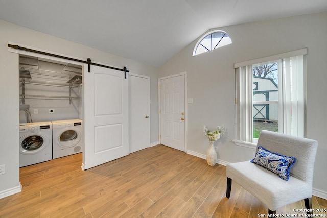 sitting room with washer and dryer, plenty of natural light, a barn door, and vaulted ceiling