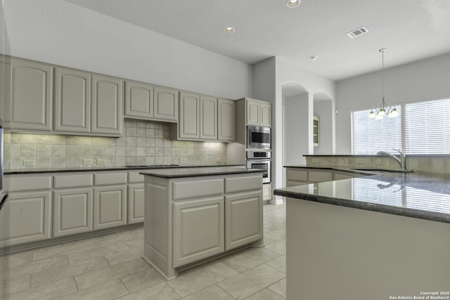 kitchen with hanging light fixtures, sink, tasteful backsplash, a center island, and stainless steel appliances