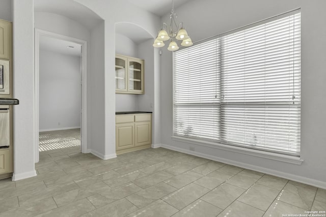 unfurnished dining area with light tile patterned floors and a notable chandelier