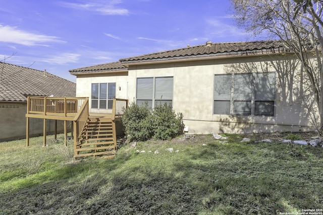 rear view of property featuring a lawn and a deck