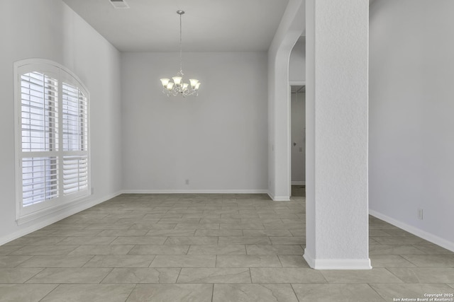 tiled empty room featuring an inviting chandelier