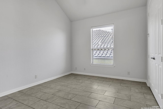 tiled spare room featuring lofted ceiling