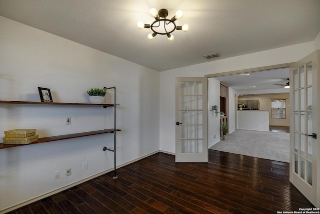 spare room featuring wood-type flooring, french doors, and an inviting chandelier