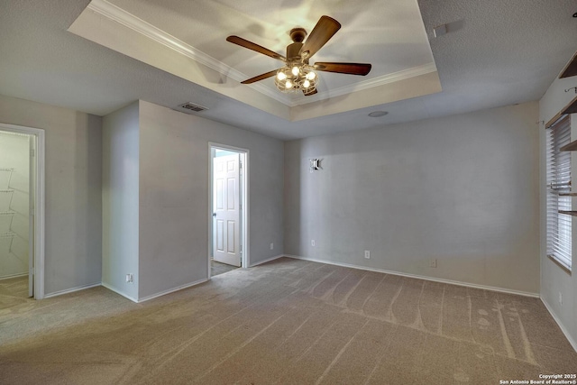 carpeted empty room featuring ceiling fan, crown molding, a textured ceiling, and a tray ceiling