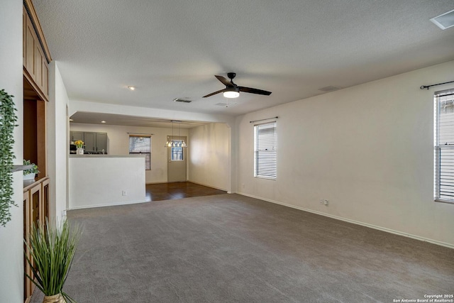 unfurnished living room with ceiling fan, dark carpet, and a textured ceiling