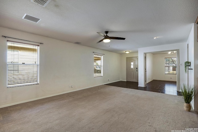 carpeted spare room featuring ceiling fan, a wealth of natural light, and a textured ceiling