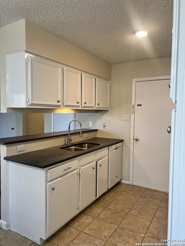 kitchen featuring white dishwasher, a textured ceiling, white cabinetry, light tile patterned floors, and sink