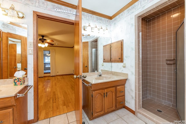 bathroom featuring tile patterned floors, ornamental molding, tiled shower, and vanity