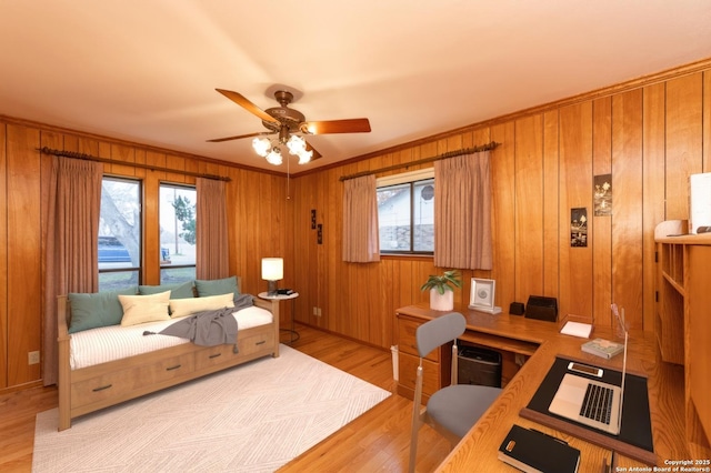 interior space with crown molding, wood walls, light hardwood / wood-style floors, and ceiling fan