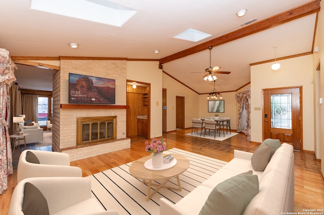 living room featuring light hardwood / wood-style flooring, a fireplace, and vaulted ceiling with skylight