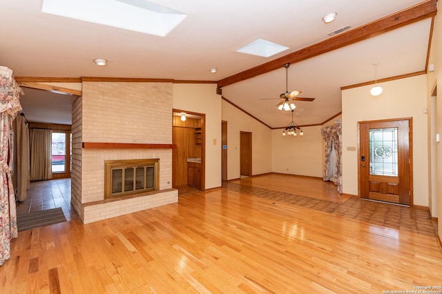 unfurnished living room with a brick fireplace, light hardwood / wood-style flooring, lofted ceiling with skylight, and ceiling fan