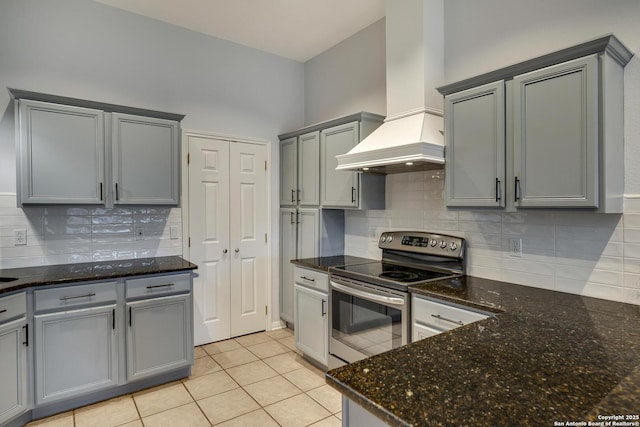 kitchen featuring gray cabinets, backsplash, light tile patterned flooring, custom exhaust hood, and stainless steel range with electric cooktop