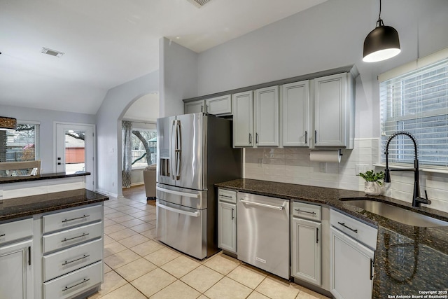 kitchen with sink, stainless steel appliances, tasteful backsplash, light tile patterned flooring, and vaulted ceiling