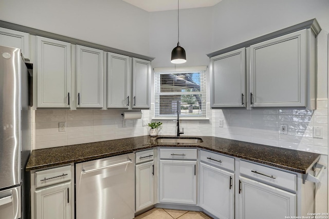 kitchen with tasteful backsplash, appliances with stainless steel finishes, sink, and dark stone countertops