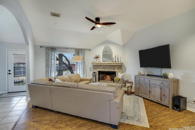 living room with lofted ceiling, a brick fireplace, a healthy amount of sunlight, and ceiling fan