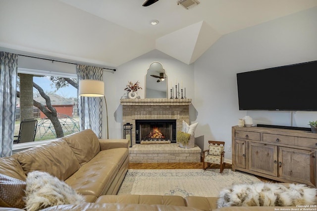 living room with ceiling fan, lofted ceiling, a fireplace, and light hardwood / wood-style flooring